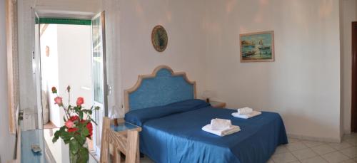 a bedroom with a blue bed and a window at Hotel Villa Cimmentorosso in Ischia