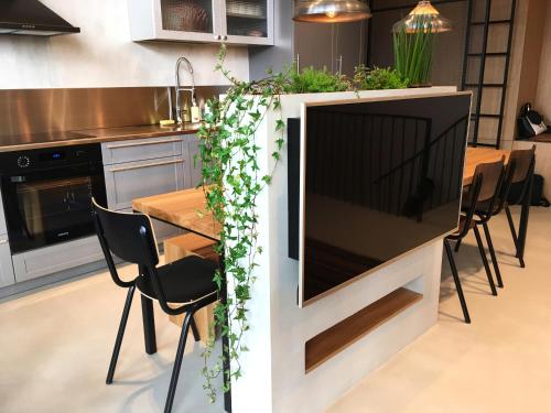 een grote televisie in een keuken met een tafel en stoelen bij G - Owl Jazz - Modern and spacious loft type apartment 8 with free private parking in Kaunas