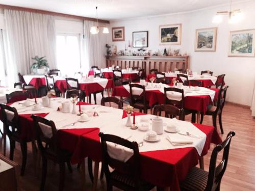 a dining room with tables and chairs with red table cloth at Garni Hirsch in Canazei