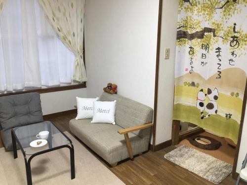 a living room with a couch and a chair at Happy Apartment in Sapporo