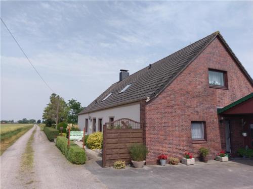 een stenen huis met een hek en een onverharde weg bij up de Pfahldeichsweg in Neugarmssiel