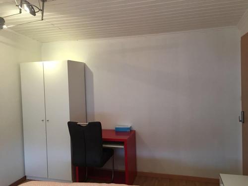 a red desk with a black chair next to a white cabinet at Apartment CHEZ TONY in Strassen