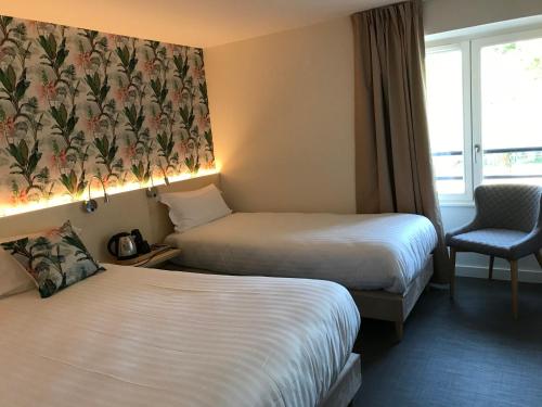 a hotel room with two beds and a chair at Hôtel-Restaurant "Les Rochers" in La Balme-de-Sillingy