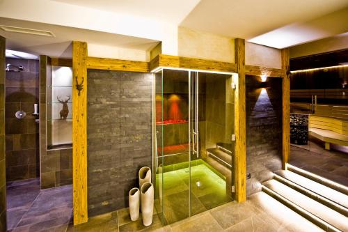 una ducha con puerta de cristal en un baño en Hotel Birkenhof, en Saalbach Hinterglemm