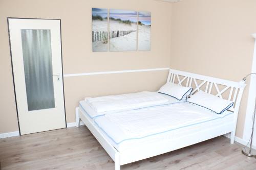 un letto bianco in una stanza bianca con specchio di 2Zi-Ferienwohnung am Südstrand mit eigenem Parkplatz perfekt für Familie a Burgtiefe auf Fehmarn 