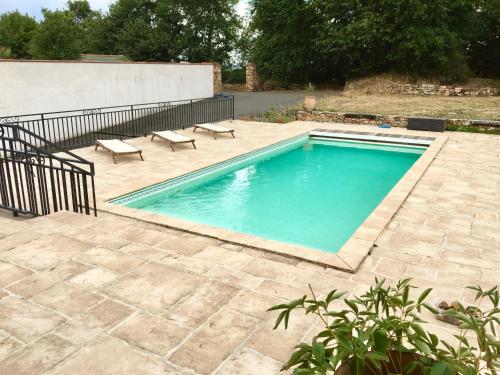 une piscine avec deux bancs à côté d'un patio dans l'établissement Gîte la Treille, à Cholet