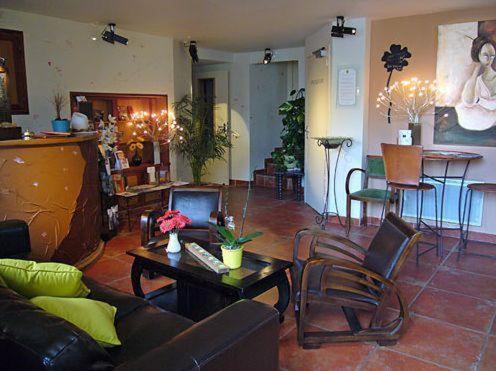 a living room with a couch and a table and chairs at Hotel O2B Aux Berges de Brocéliande in Beignon