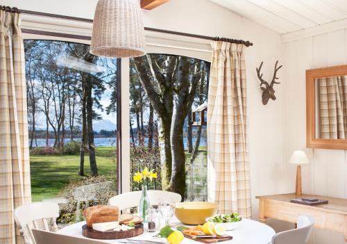 a dining room with a table and a large window at Lochend Chalets in Port of Menteith