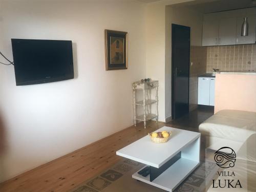 a living room with a table and a tv on a wall at Apartments Villa Luka in Sveti Stefan