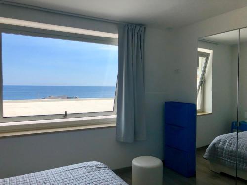 a bedroom with a window with a view of the beach at Casa Sara in Acireale