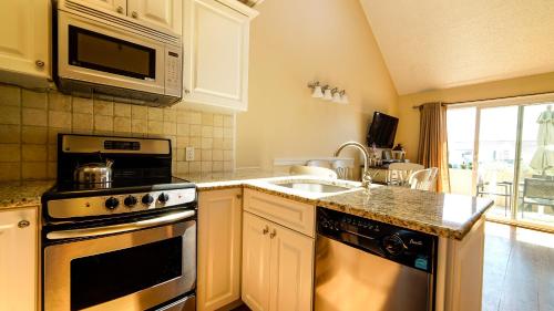 a kitchen with a stove and a sink and a microwave at Windward Shores in Amagansett