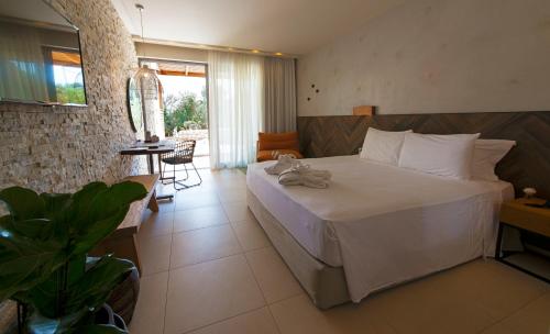 a bedroom with a large bed and a table with a chair at Port Royal Villas and Spa - Adults Only in Kolymbia