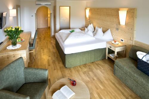 ein Hotelzimmer mit einem großen Bett und zwei Sofas in der Unterkunft Schwarzer Adler in Seis am Schlern