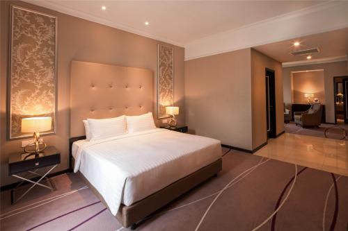 a bedroom with a large bed and a living room at Dorsett Hartamas Kuala Lumpur in Kuala Lumpur