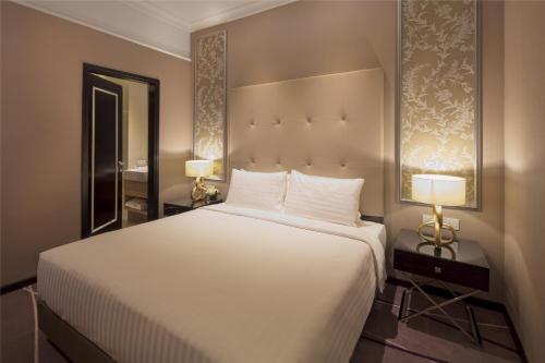 a bedroom with a large white bed with two lamps at Dorsett Hartamas Kuala Lumpur in Kuala Lumpur