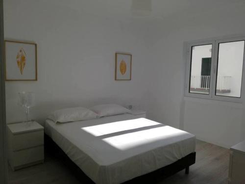 a white bedroom with a bed and a window at Azores Calheta Inn Apartment T3 in Ponta Delgada