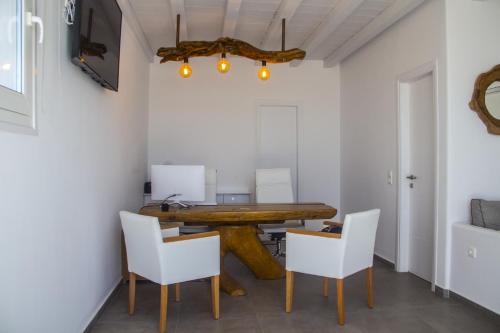 a dining room with a wooden table and white chairs at Eternal Suites in Mýkonos City