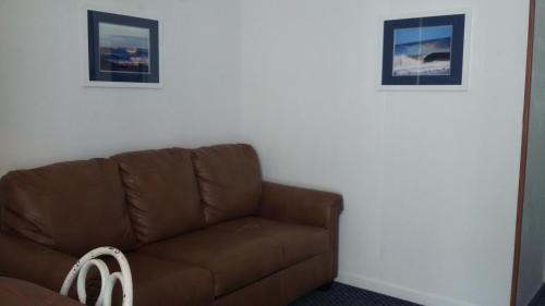 a brown couch in a living room with two pictures at Tide Winds Motel in Wildwood