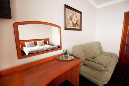 a bedroom with a bed and a chair and a mirror at Hotel Wodnik Twój Hotel z widokiem na morze in Ustronie Morskie