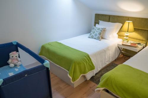 a bedroom with two beds and a teddy bear sitting on a bench at Casa Da Trigueira in Santa Eugénia