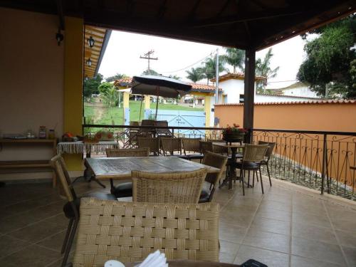 um pátio com mesas e cadeiras e um guarda-sol em Pousada Vila Cocais em Cocais