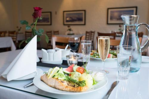 a table with a plate of food and glasses of wine at Glomfjord Hotel in Glomfjord