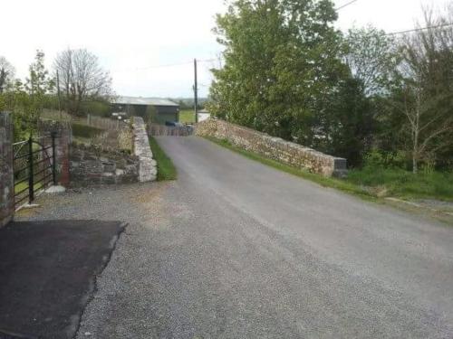 an empty road with a stone wall and a fence at Relaxing Break at Coshel View in Foyle Bridge