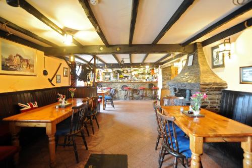 a restaurant with wooden tables and chairs and a fireplace at The West Country Inn in Clovelly