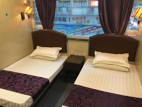 two beds in a room with a window at Kowloon YOUTH Village Tsim Sha Tsui 九龙青年公寓 in Hong Kong