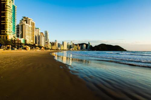 a beach with tall buildings and the ocean at Hotel Gumz in Balneário Camboriú