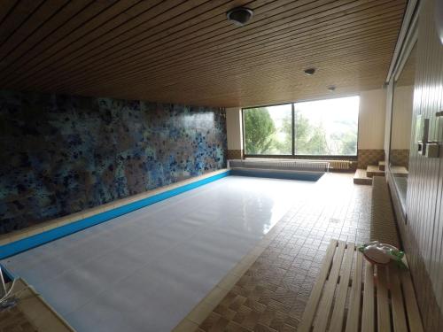 an empty swimming pool with a bench in a room at Villa-Fuldablick in Morschen
