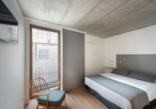 1 dormitorio con 1 cama, 1 silla y 1 ventana en Hotel SempreFisterra, en Finisterre