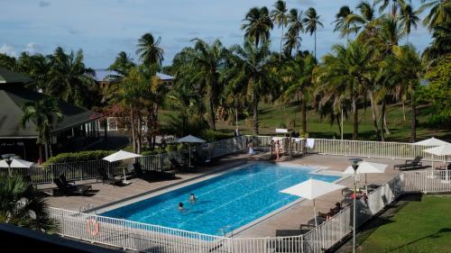 an overhead view of a swimming pool with palm trees at Grand Hotel Montabo in Cayenne