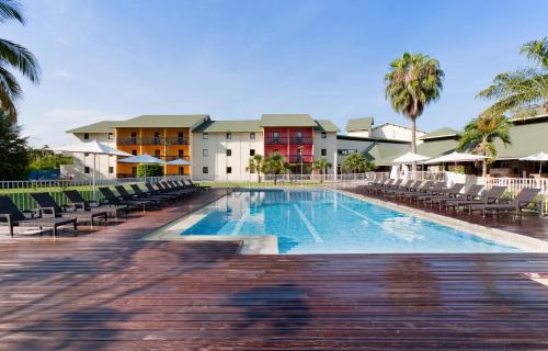 - une piscine dans un complexe avec des chaises et un bâtiment dans l'établissement Grand Hotel Montabo, à Cayenne