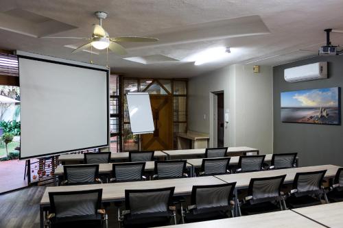 a conference room with a large projection screen and chairs at Polo Guest House in Polokwane
