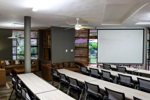a conference room with tables and chairs and a screen at Polo Guest House in Polokwane