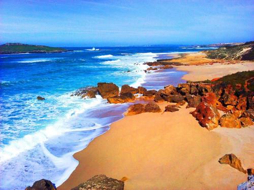 an aerial view of a beach with rocks and water at Quartos Abelha in Porto Covo