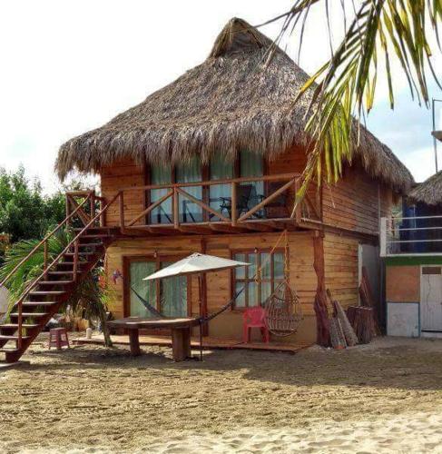 a wooden house with a bench and a thatch roof at Cabañas La Isla Chacahua in Guayabas