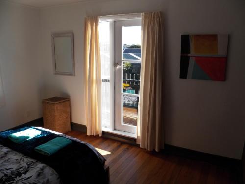 1 dormitorio con puerta que da a un balcón en The Crawford's, en Invercargill
