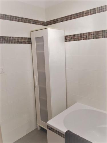 une salle de bain blanche avec une douche et un lavabo dans l'établissement Appartement de Louise proche aéroport, à Lucciana