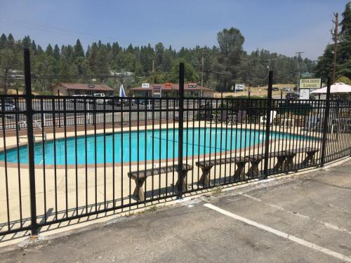 a swimming pool behind a fence with two benches at Holiday Lodge in Grass Valley