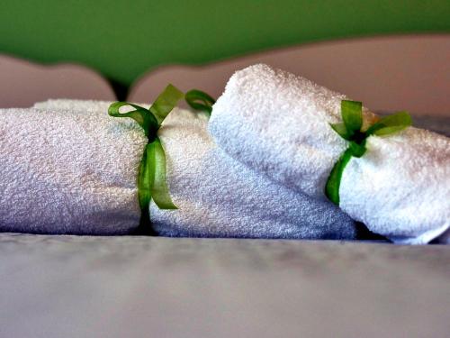 a pair of white towels with green ribbon at Sweet Home in LʼAquila