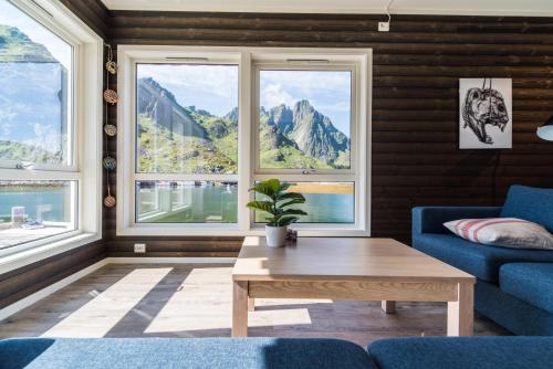 a living room with a table and windows at Hemmingodden Lodge in Ballstad