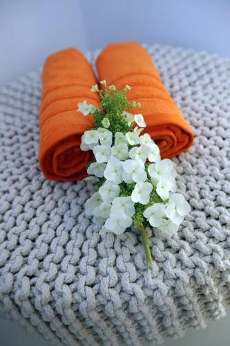 two orange towels and a bouquet of flowers on a towel at B&B PETIT PRINCE, GENT in Ghent