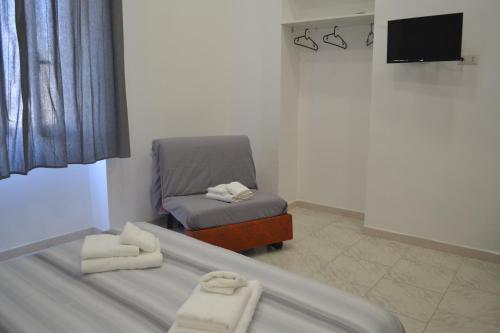 Habitación con cama, silla y TV. en ANTOS 013 en Nápoles