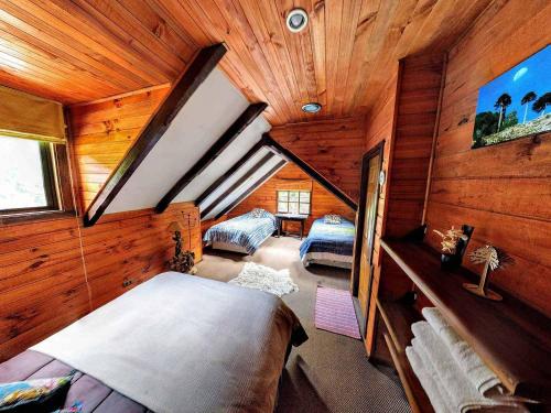 a attic room with two beds in a cabin at Refugio Las Raices in Malalcahuello