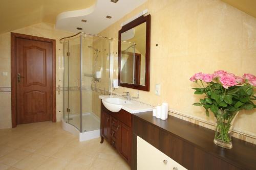 uma casa de banho com um lavatório e um chuveiro com rosas rosas em Apartamenty Dorotowo em Dorotowo