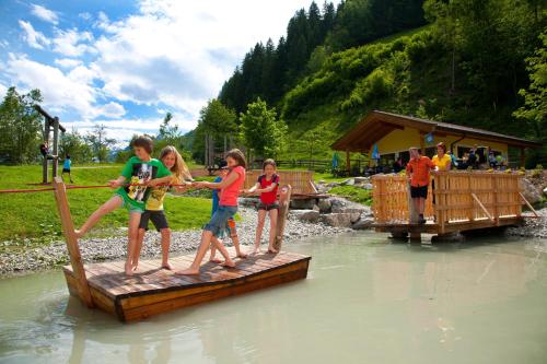 a group of children crossing a wooden bridge in the water at Apartment Gästehaus Luggau in Rauris