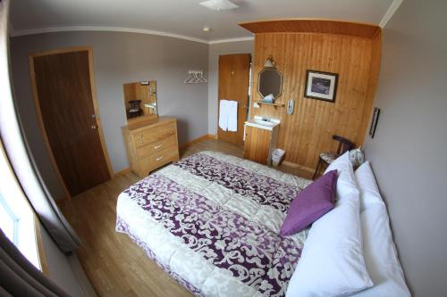 a bedroom with a large bed and a mirror at Hébergement Maison Fortier in Tadoussac