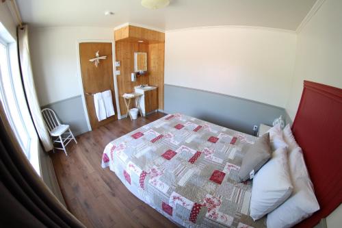 a bedroom with a bed with a quilt on it at Hébergement Maison Fortier in Tadoussac